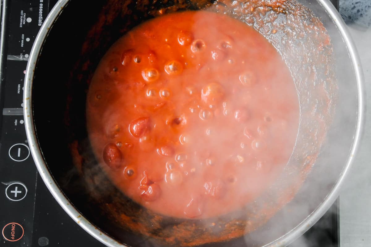 overhead image of making tomato sauce in a skillet. 