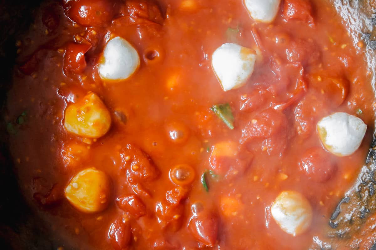overhead image of making tomato sauce and adding in mozzarella cheese.