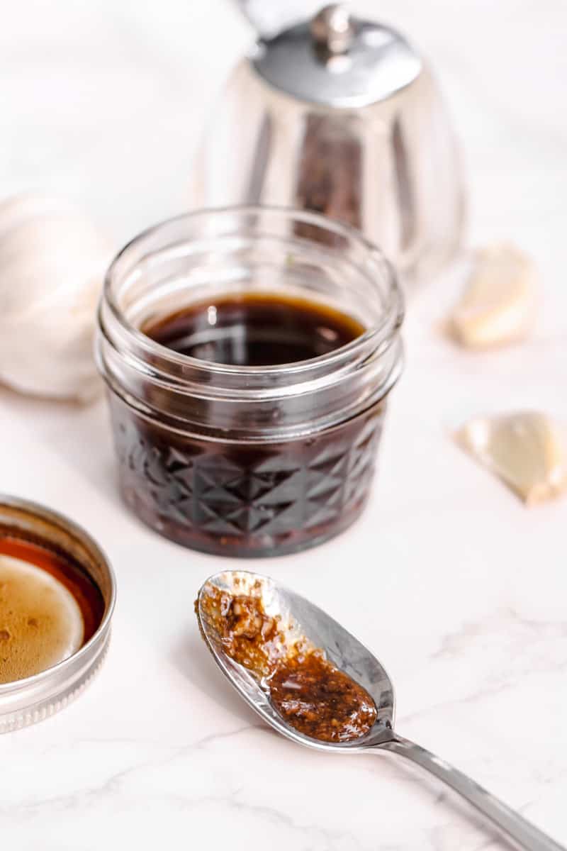 close up image of vinaigrette in a jar and a spoon.