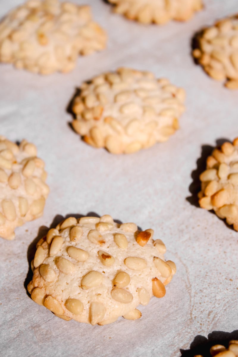 close up image of pignoli cookies on a baking sheet.