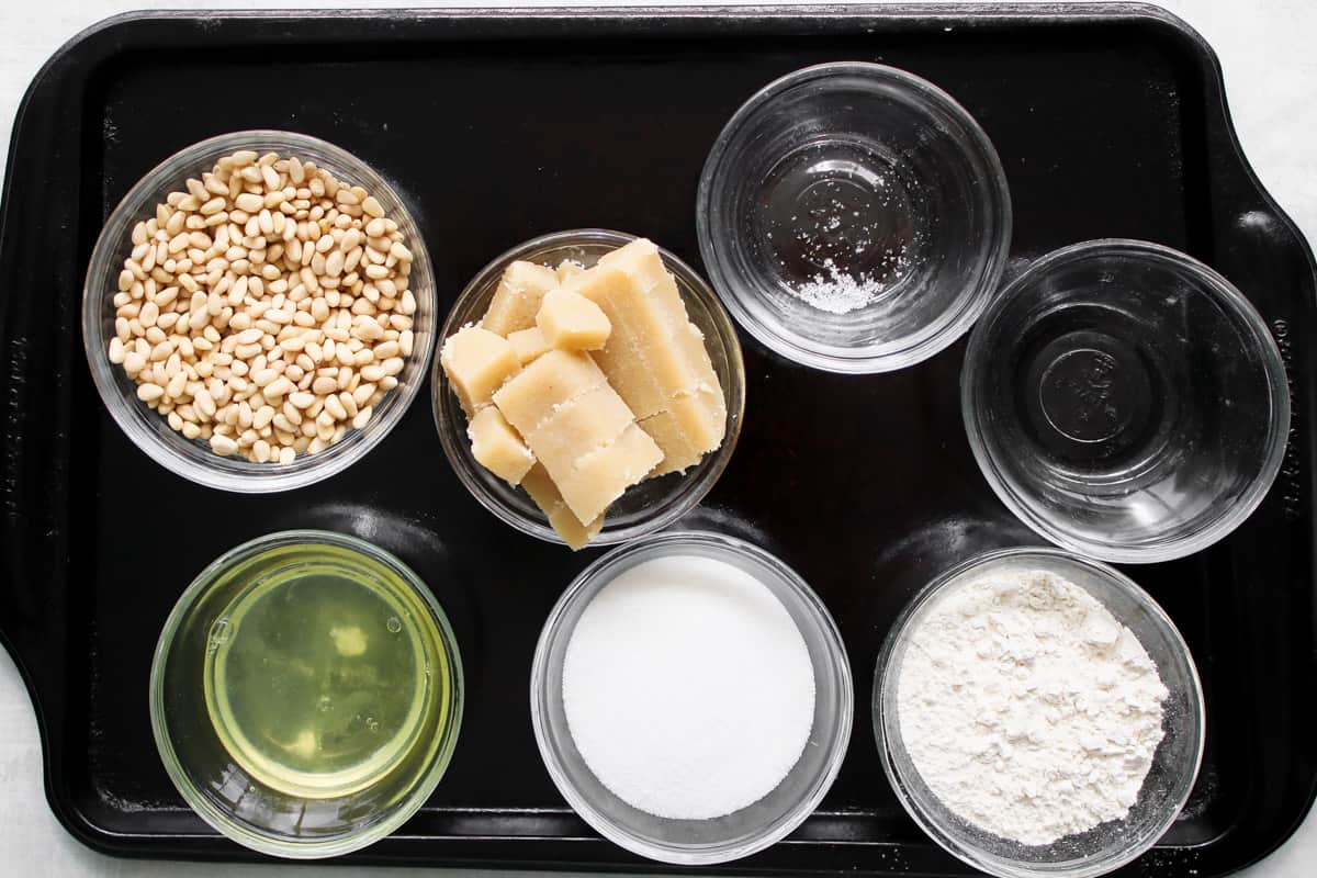 ingredients to make pignoli cookies on a baking tray.