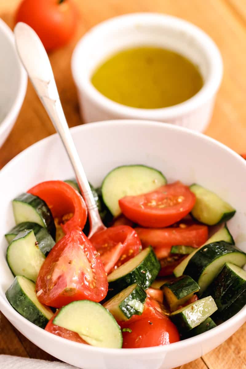 close-up image of tomato cucumber salad in a white bowl. 