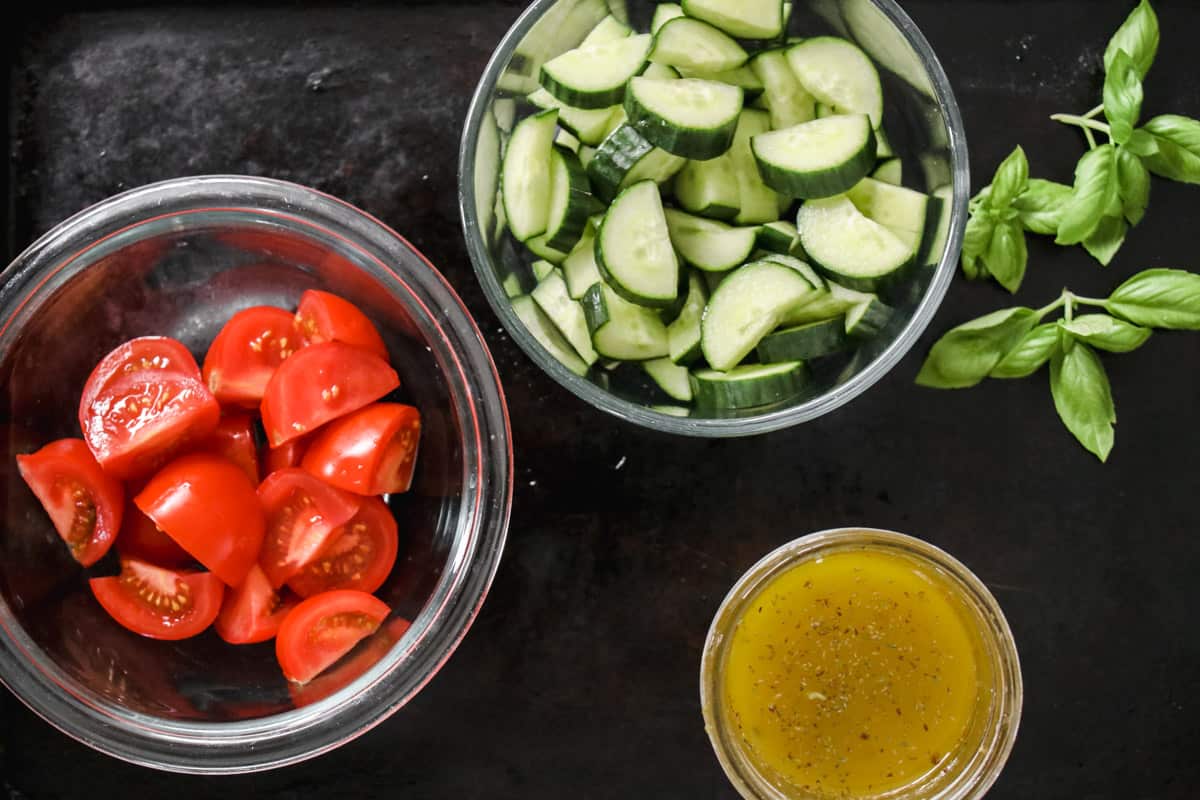 ingredients in glass bowl to make tomato and cucumber salad. 