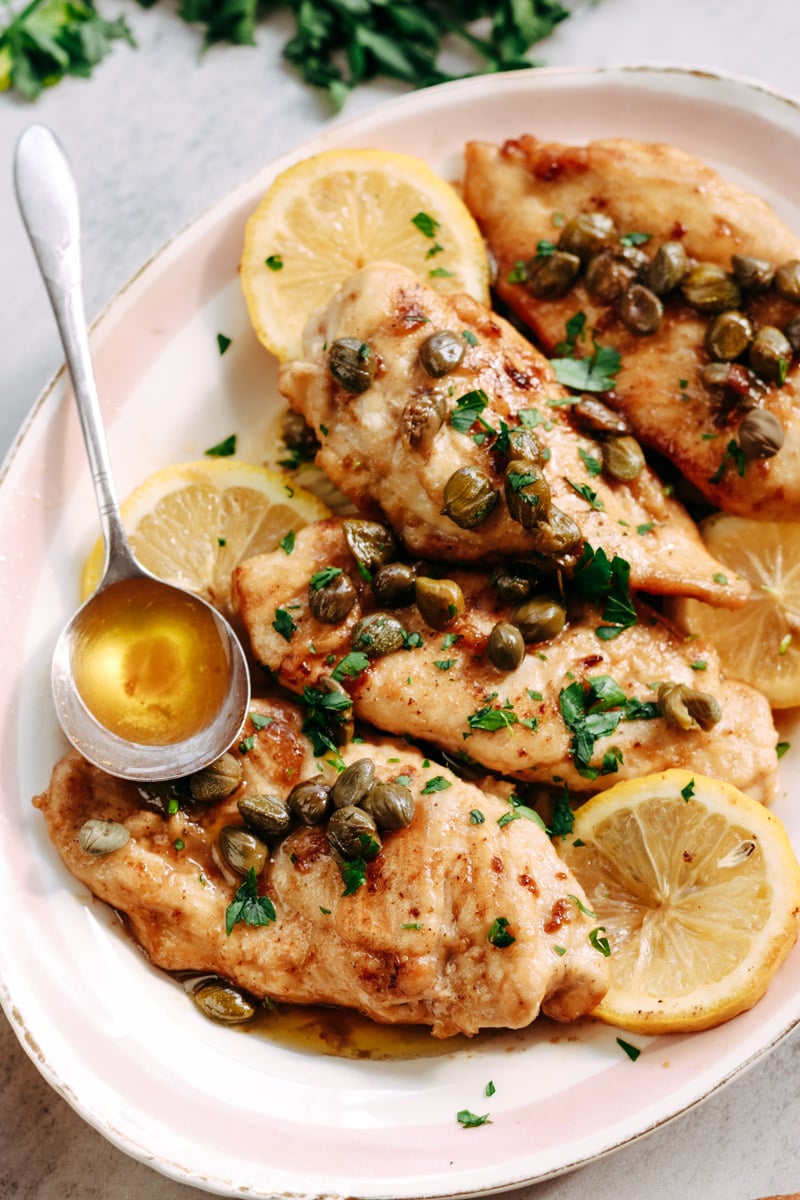 overhead image of chicken piccata with lemon slices on a serving plate.