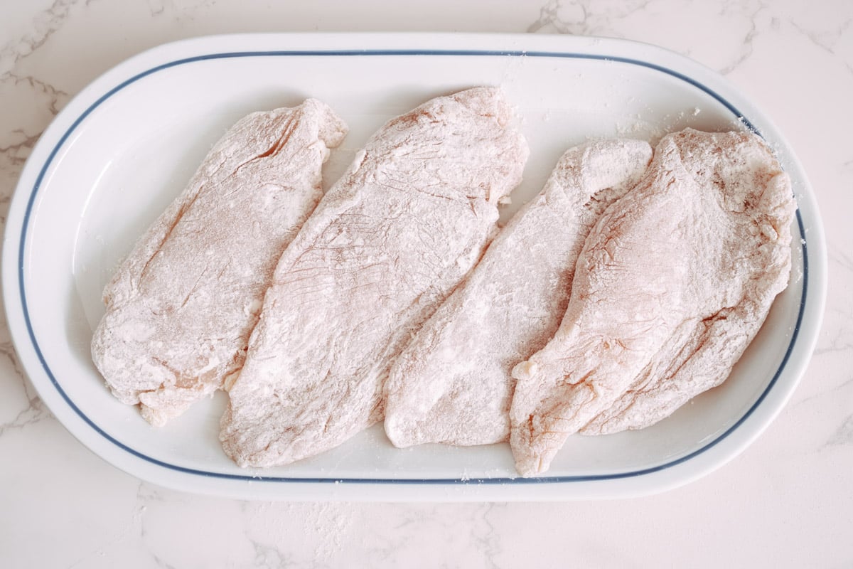 overhead image of chicken dredged in flour on a serving plate.
