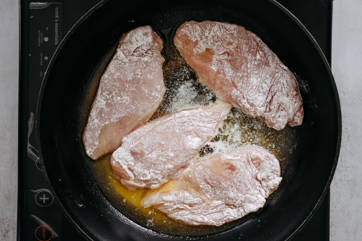 overhead image of cooking chicken cutlets in a skillet.