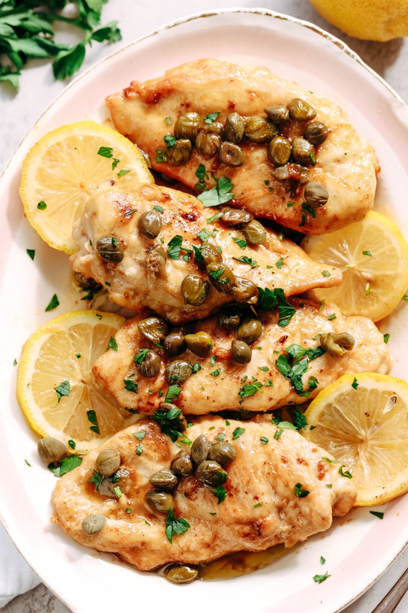 close up image of chicken piccata with lemon slices on a serving plate.
