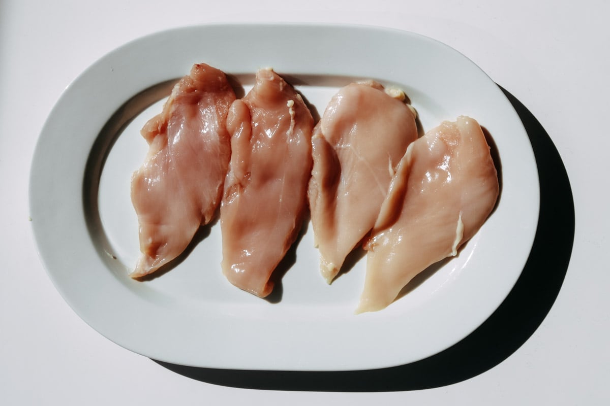 overhead image of chicken breasts on a white platter.
