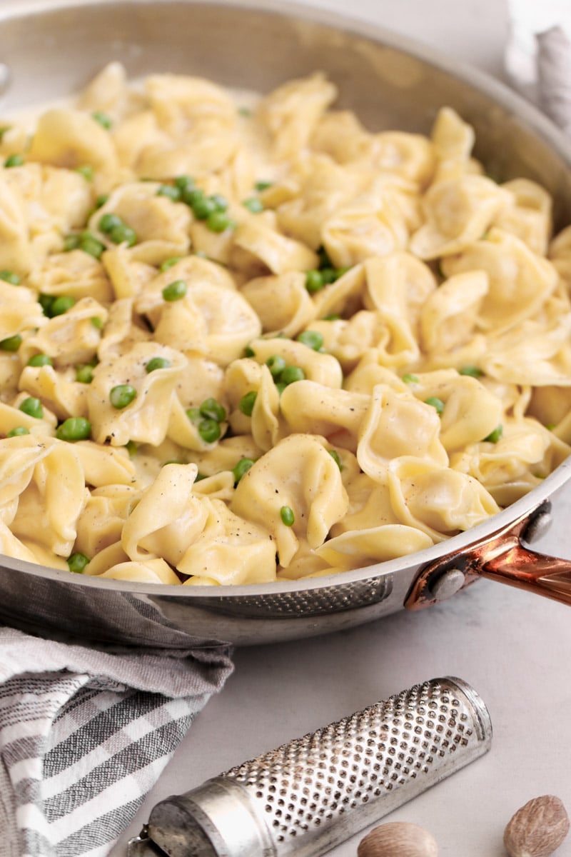 close up image of tortellini alla panna in a pan.