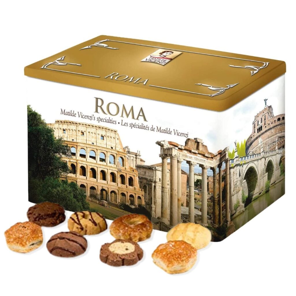 A close-up shot of a Matilde Vicenzi Roma Cookie Tin cleverly displayed on packaging printed in a beautiful tin featuring a variety of Italian bakery goods. The baked goods are carefully sealed in trays inside the tin, showcasing its craftsmanship and variety in detail. A picture of Matilde Vicenzi, an Italian special cookie brand, this product is perfect as a bakery gift for moms.