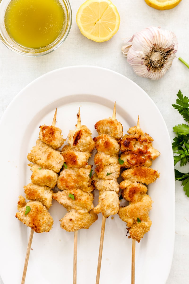 overhead image of chicken skewers on a white platter.