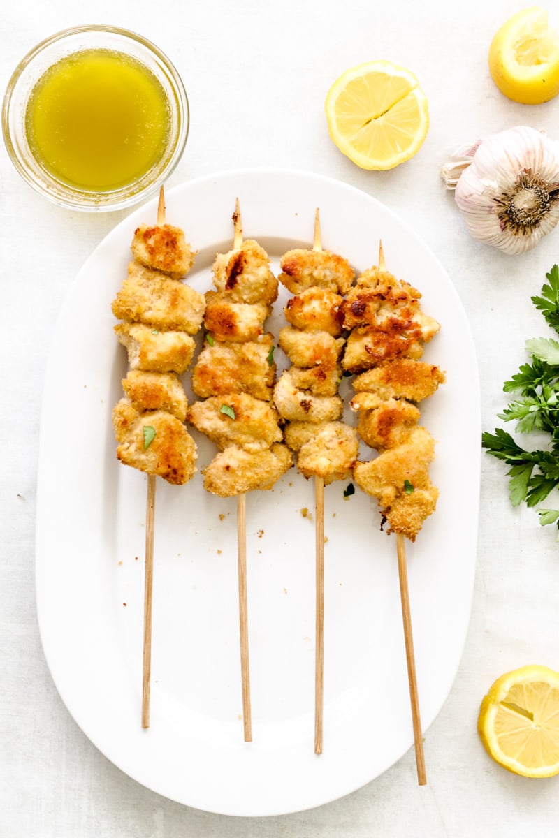 overhead image of chicken skewers on a white platter.