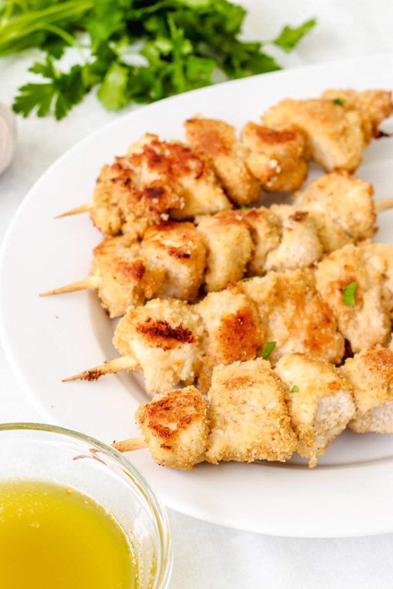 overhead image of chicken spiedini on a white plate with parsley in the background.