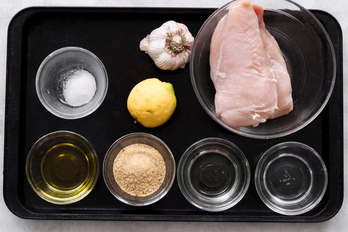 overhead image of ingredients to make chicken skewers on a baking sheet.