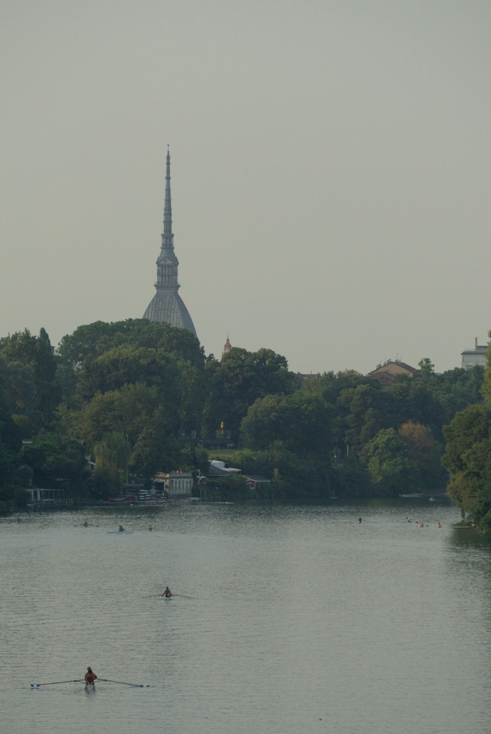 Canoes sailing on the Po River in Turin offer a serene scene, with the iconic Mole Antonelliana towering majestically in the background. In the middle ground, the lush trees of Parco del Valentino add a touch of verdant beauty, enhancing the picturesque setting. Is Turin worth visiting? Absolutely! This idyllic image highlights the city's unique blend of natural landscapes and historic landmarks, making it a perfect destination for nature lovers and history enthusiasts alike.