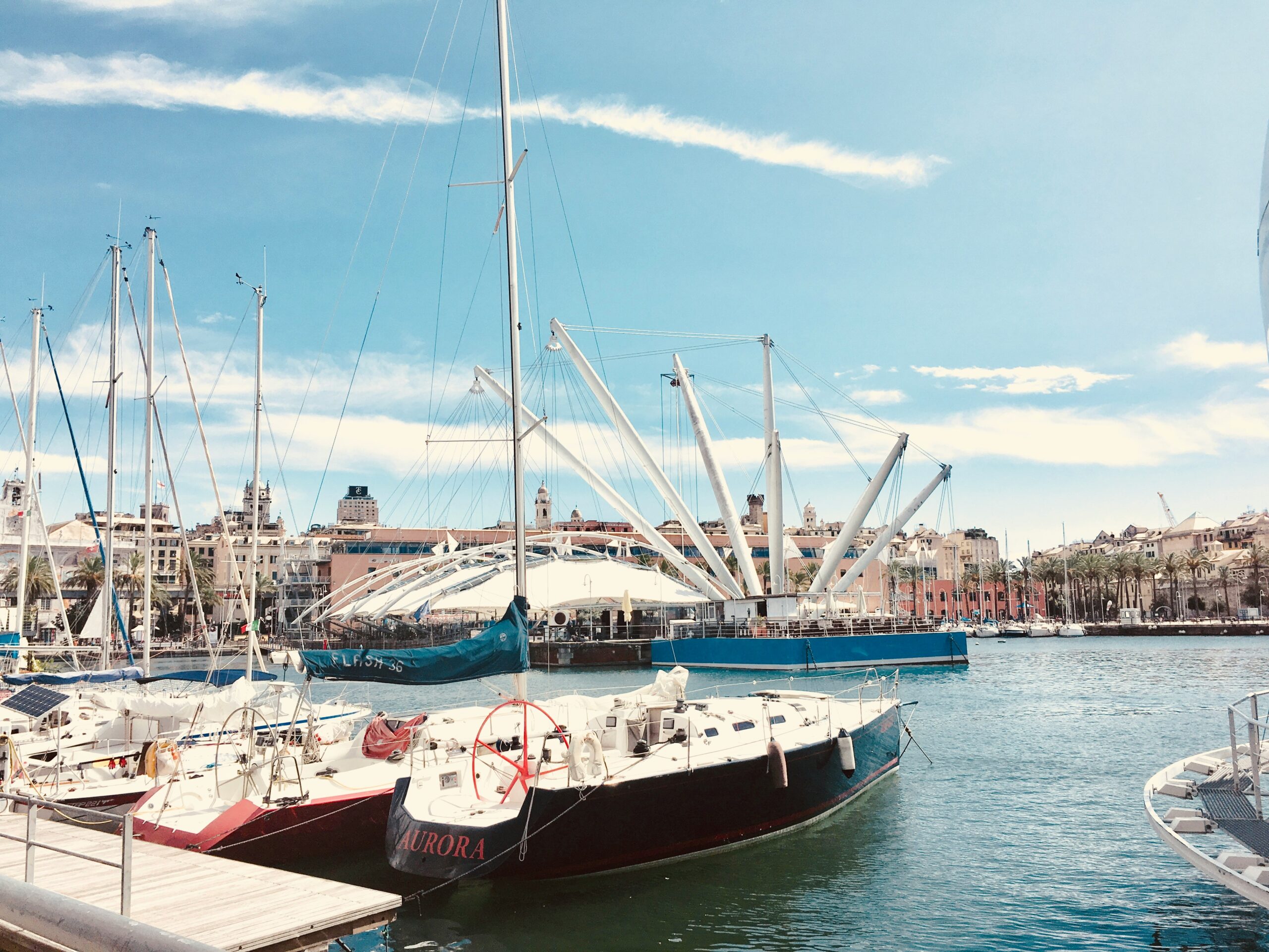The photograph captures a serene view of a small port in Genoa, Italy. The port is nestled along the coastline, with a collection of modest boats gently bobbing in the calm waters. Surrounding the harbor, you can see quaint buildings with colorful facades, reflecting the rich maritime heritage of the area. The scene is tranquil, with the gentle sound of waves lapping against the boats and the soft glow of the early morning or late afternoon light. This small port, with its intimate scale and picturesque surroundings, offers a glimpse into the everyday life and charm of Genoa's coastal communities.