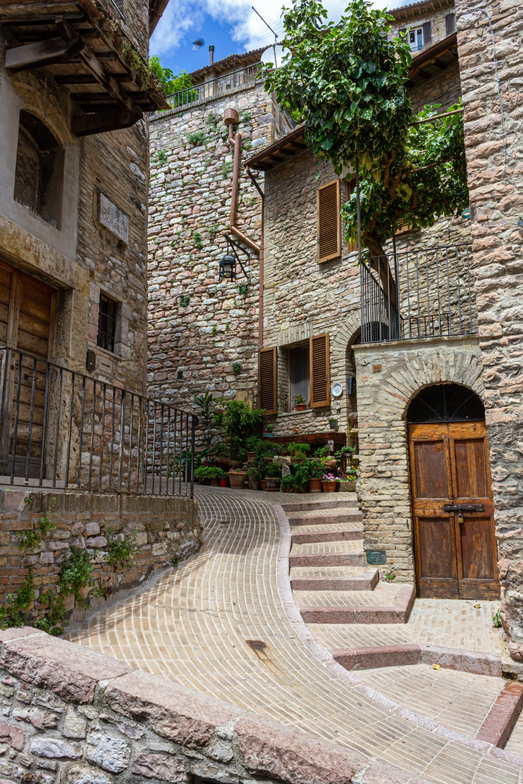A charming residential corner in Perugia, Italy, featuring narrow cobblestone streets lined with quaint stone houses adorned with terracotta roofs and wooden shutters. Vibrant flower boxes and climbing ivy add a touch of natural beauty to the scene. Cozy balconies and rustic lanterns enhance the warm, inviting atmosphere. This picturesque setting epitomizes the timeless charm and historic elegance of Perugia's residential neighborhoods.