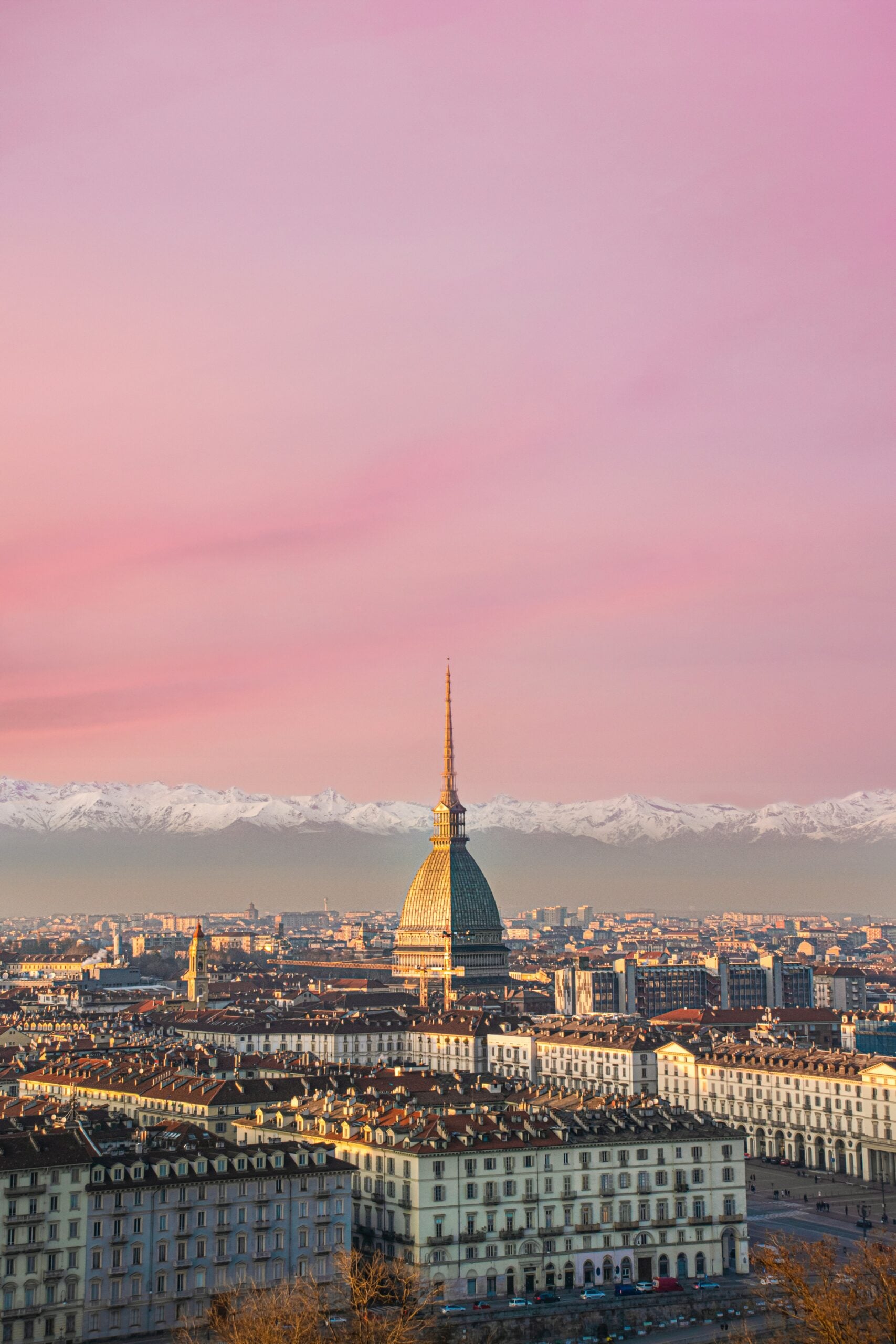 An aerial view of the city of Turin reveals a stunning panorama with the Alps majestically rising in the background. The city's intricate layout of historic buildings, modern architecture, and verdant parks is beautifully framed by the towering mountain range. Is Turin worth visiting? Absolutely! This breathtaking perspective showcases the harmonious blend of urban sophistication and natural beauty, making Turin an irresistible destination for travelers seeking a unique and picturesque experience.