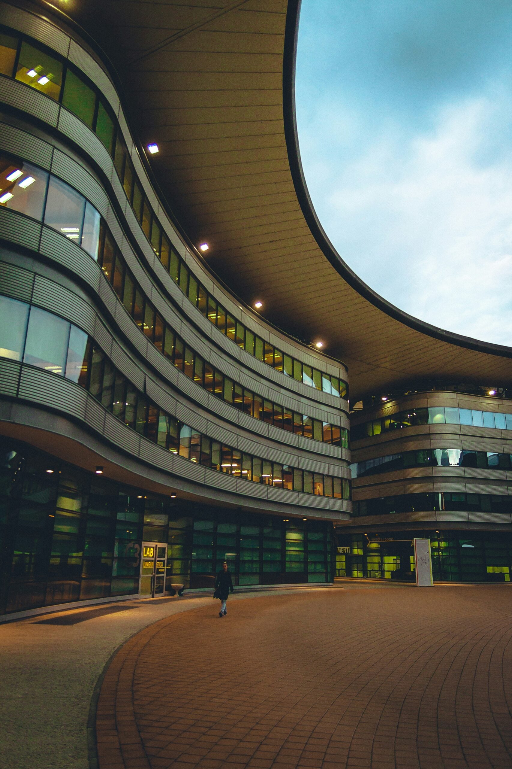 The front of a modern building in Turin features sleek, contemporary design elements. The facade is characterized by clean lines, expansive glass windows, and minimalist aesthetics, reflecting the city's blend of innovation and tradition. Is Turin worth visiting? Absolutely! This striking modern architecture adds to the diverse urban landscape of Turin, making it an appealing destination for those interested in contemporary design and urban development.