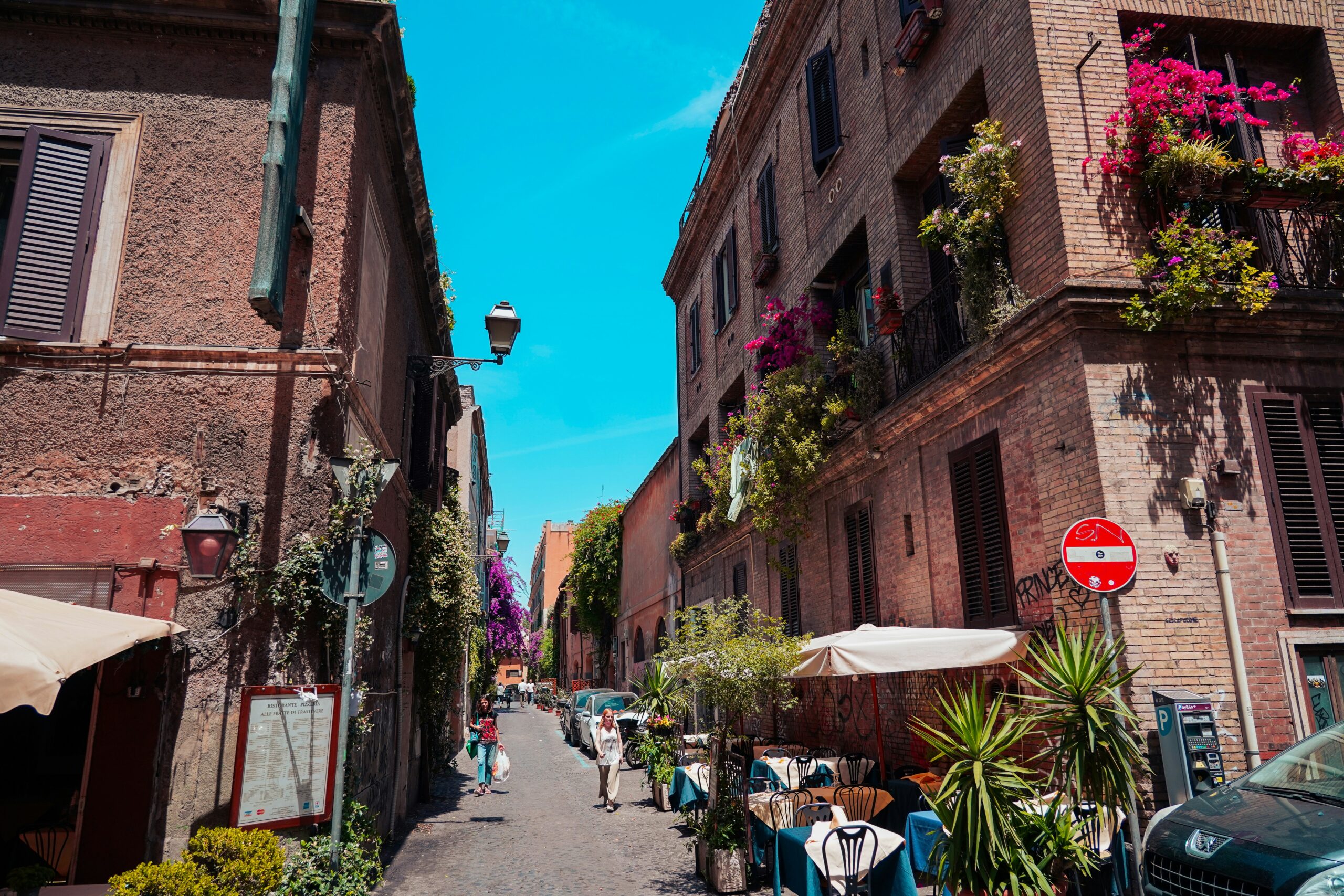 Photograph of one of the best streets in Rome, Italy, worth walking on. This captivating image features a picturesque cobblestone street lined with charming cafes, historical buildings, and vibrant flowers, embodying the essence of streets in Rome, Italy. Perfect for travel enthusiasts looking to explore the timeless beauty and cultural richness of Rome's streets.