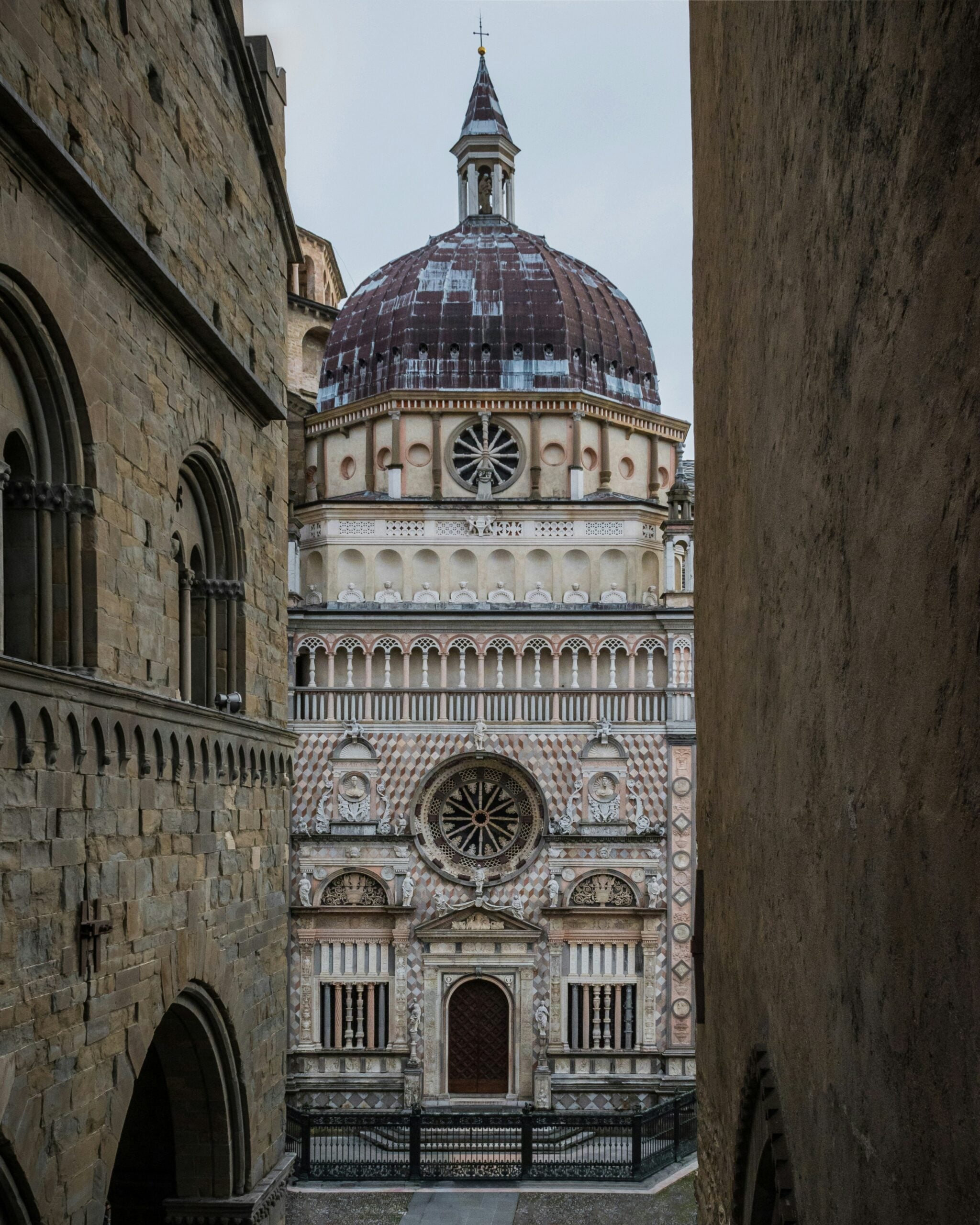 A detailed photograph of the Basilica di Santa Maria Maggiore in Bergamo, Italy, highlighting its ornate Romanesque architecture. The image captures the intricate façade adorned with elaborate sculptures, decorative stonework, and stunning frescoes that showcase the basilica's historical and artistic significance. The grand entrance, framed by majestic columns and arches, invites viewers to appreciate the rich cultural heritage of Bergamo. This iconic landmark, set against the backdrop of the picturesque Città Alta, embodies the spiritual and architectural splendor of Bergamo, Italy, making it a must-see destination for visitors.