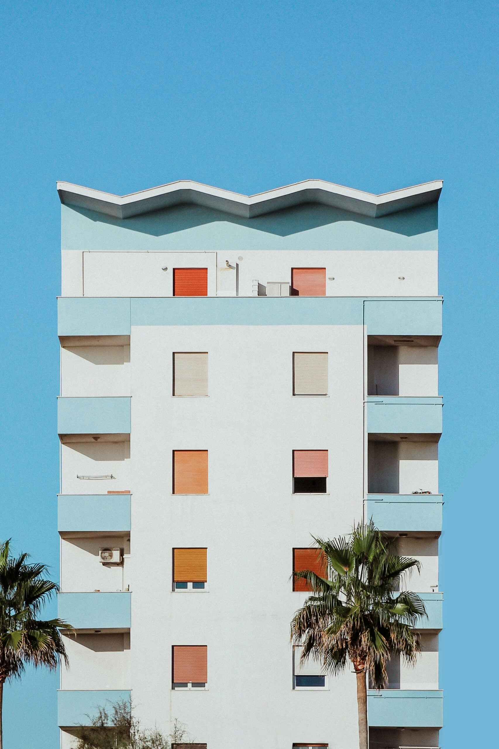 A modern residential building in Montesilvano, Pescara, Italy, featuring a sleek design with light blue and white color accents. The building's clean lines and contemporary architecture stand out against the backdrop of the nearby beach, just a short distance away. Large windows and balconies offer stunning views of the Adriatic Sea, allowing residents to enjoy the coastal scenery. The light blue and white tones of the building harmonize with the surrounding natural environment, reflecting the tranquil seaside atmosphere. This structure is a prime example of modern coastal living in the picturesque setting of Montesilvano, Pescara.