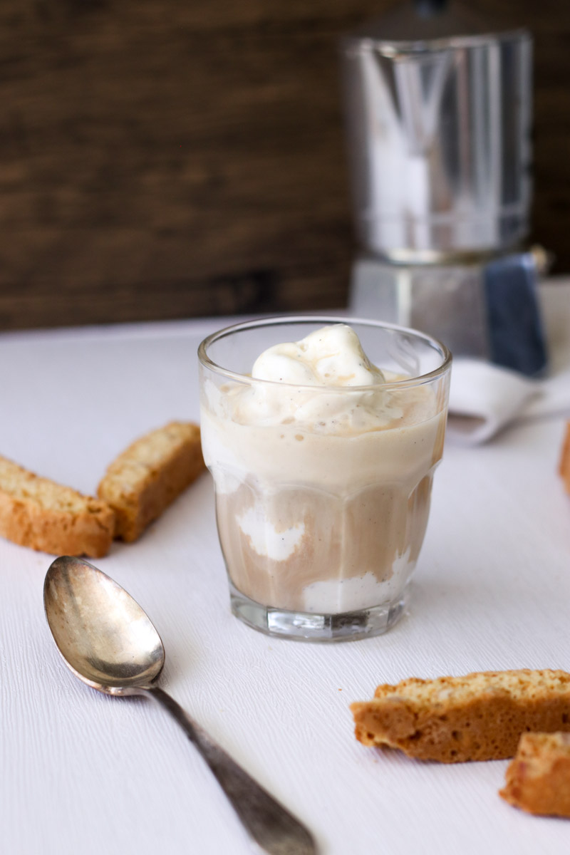 close up image of ice cream in a glass with biscotti in background. 