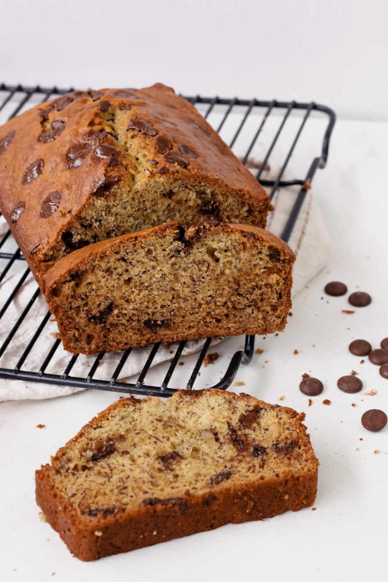close up image of sliced banana bread with chocolate chips on a cooling rack.
