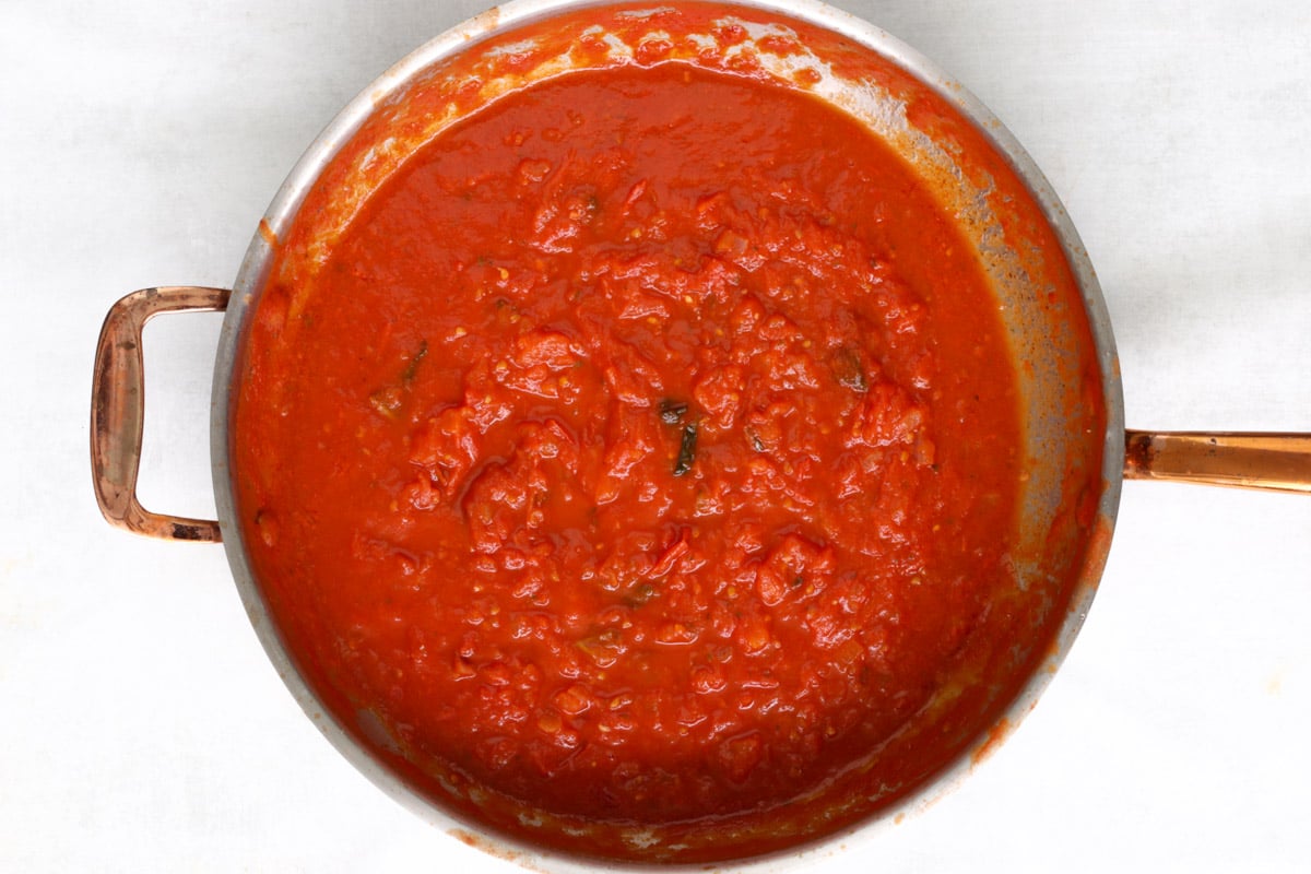 overhead image of making tomato sauce in a large skillet.