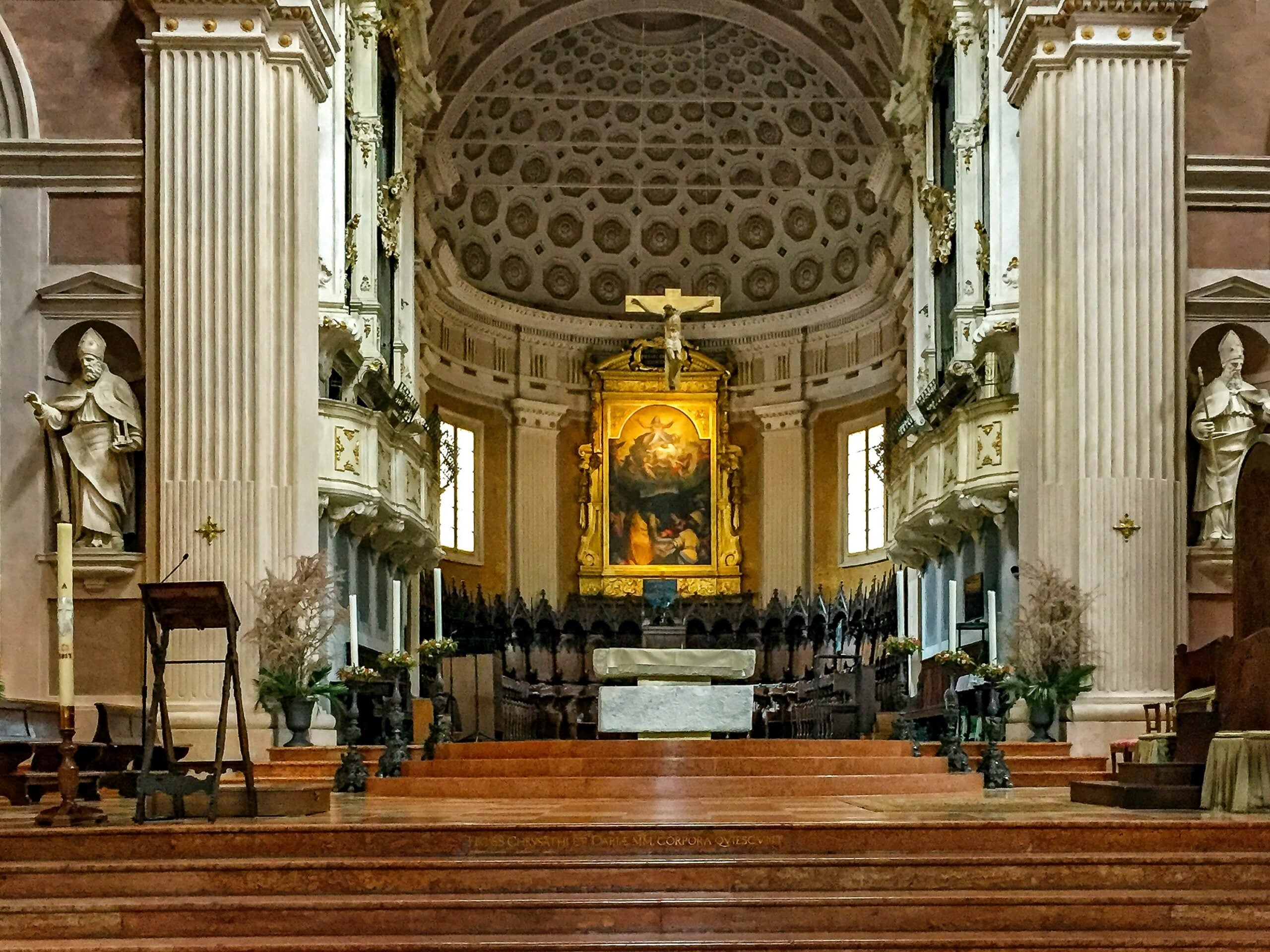 A photograph taken inside an old church in Reggio Emilia, Province of Reggio Emilia, Italy, showcases a view looking towards the altar. The image captures the church's stunning architectural details, including ornate carvings, intricate frescoes, and the soft glow of natural light filtering through stained glass windows. The altar, adorned with religious artifacts and candles, stands as the focal point, exuding a sense of reverence and history. This scene beautifully encapsulates the spiritual and cultural heritage of Reggio Emilia, Italy, inviting viewers to appreciate its sacred and historic ambiance.