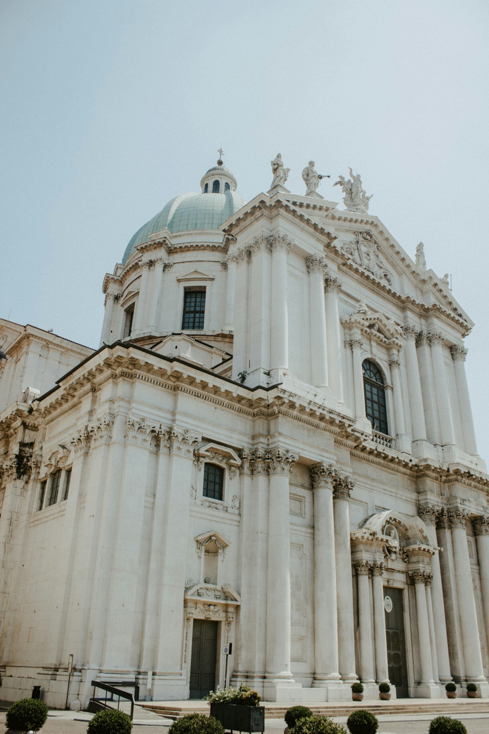 Photograph of a magnificent white cathedral in Brescia, Italy, captured under a clear blue sky. This image highlights the intricate details and grandeur of Brescia's historic architecture, making it a must-visit destination for architecture enthusiasts and travelers alike.