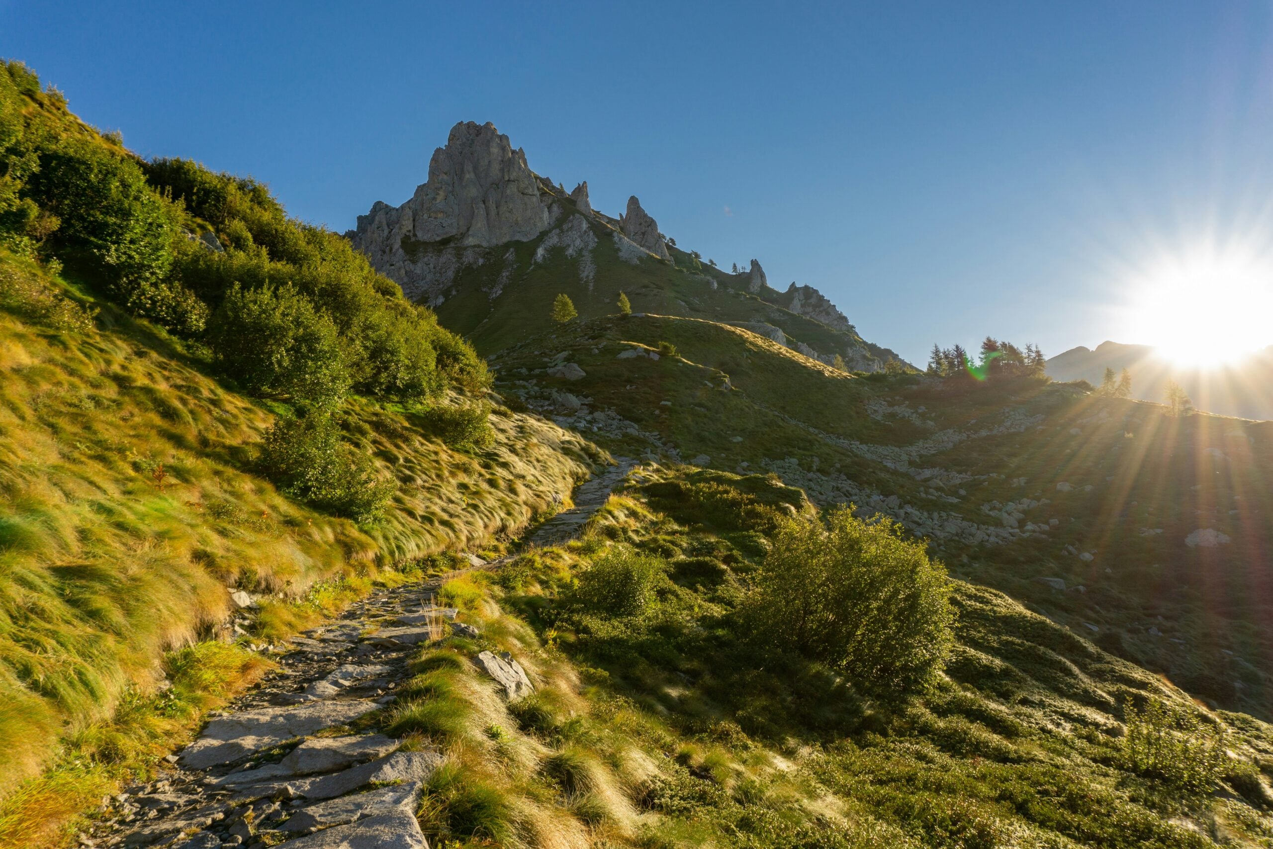 Photograph of a serene mountain trail in the Province of Brescia, Italy, showcasing the lush greenery and rugged terrain. This trail offers a peaceful escape into nature, inviting hikers and outdoor enthusiasts to explore the scenic landscapes and breathtaking views that define this region. Perfect for adventure seekers looking to experience the natural beauty of Brescia.