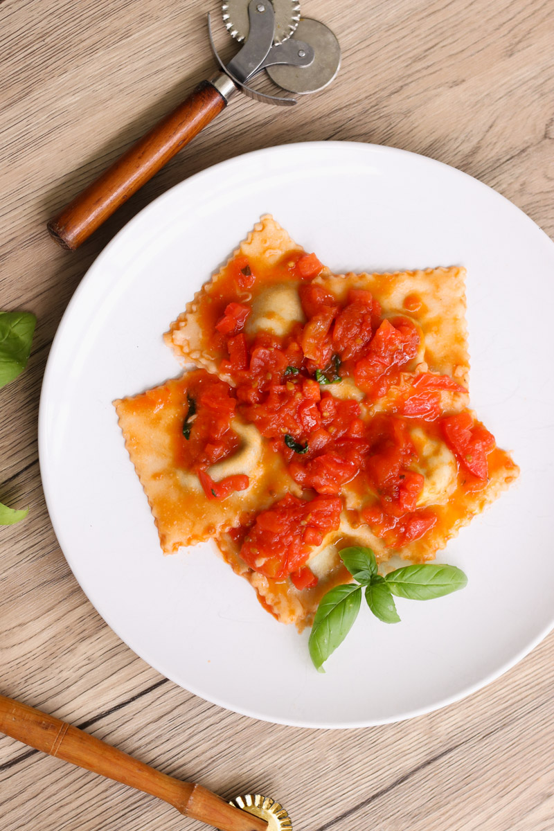 overhead image of ravioli with tomato sauce.
