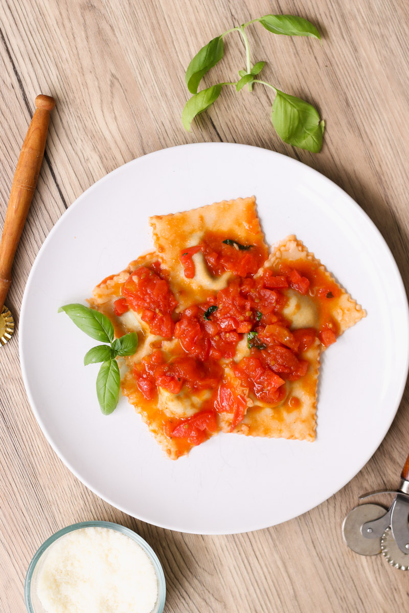 close up image of ravioli with tomato sauce on a white plate.