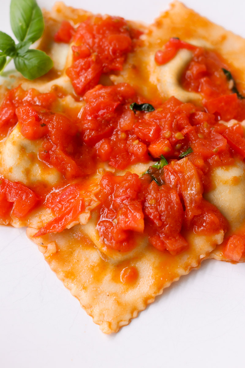 close up image of ravioli with tomato sauce.