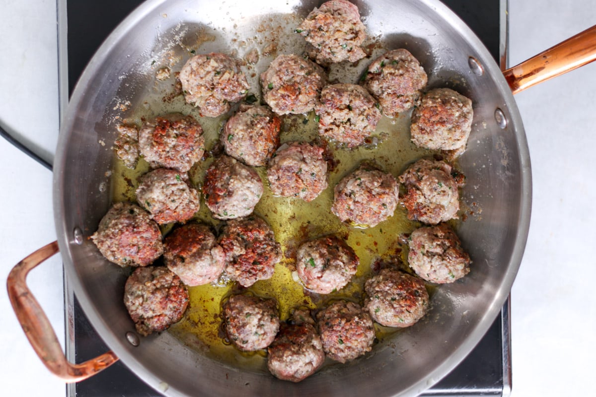 close up image of pan-frying meatballs in oil.