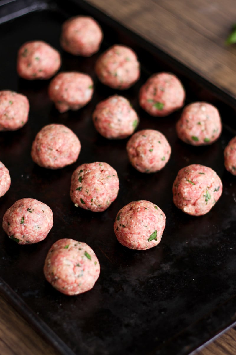 close up image of meatballs on a baking sheet.