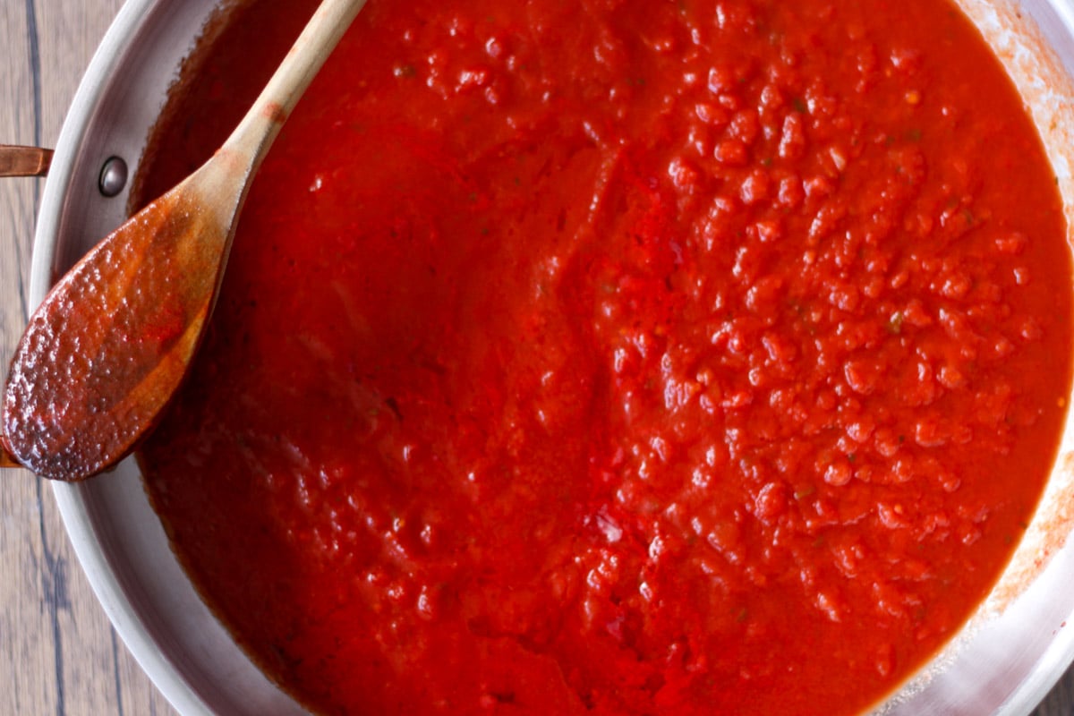 close up image of making tomato sauce in a pan.