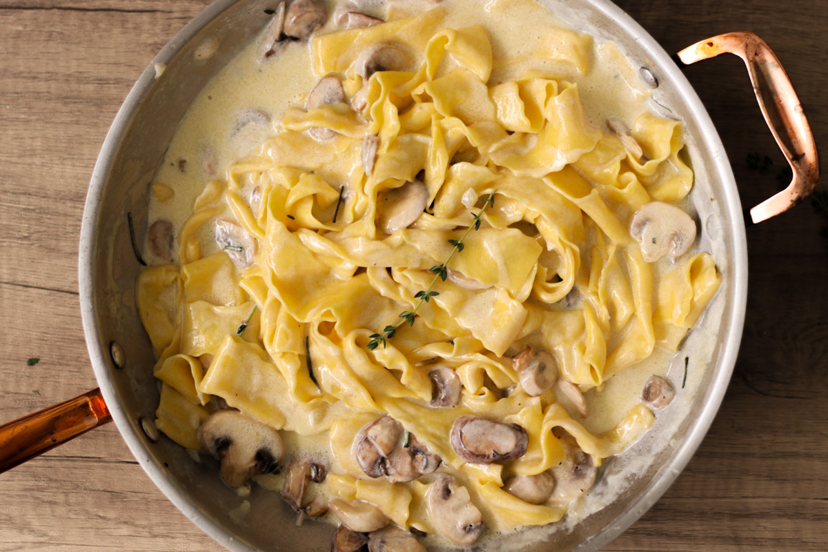 overhead image of pasta in a mushroom cream sauce in a skillet. 