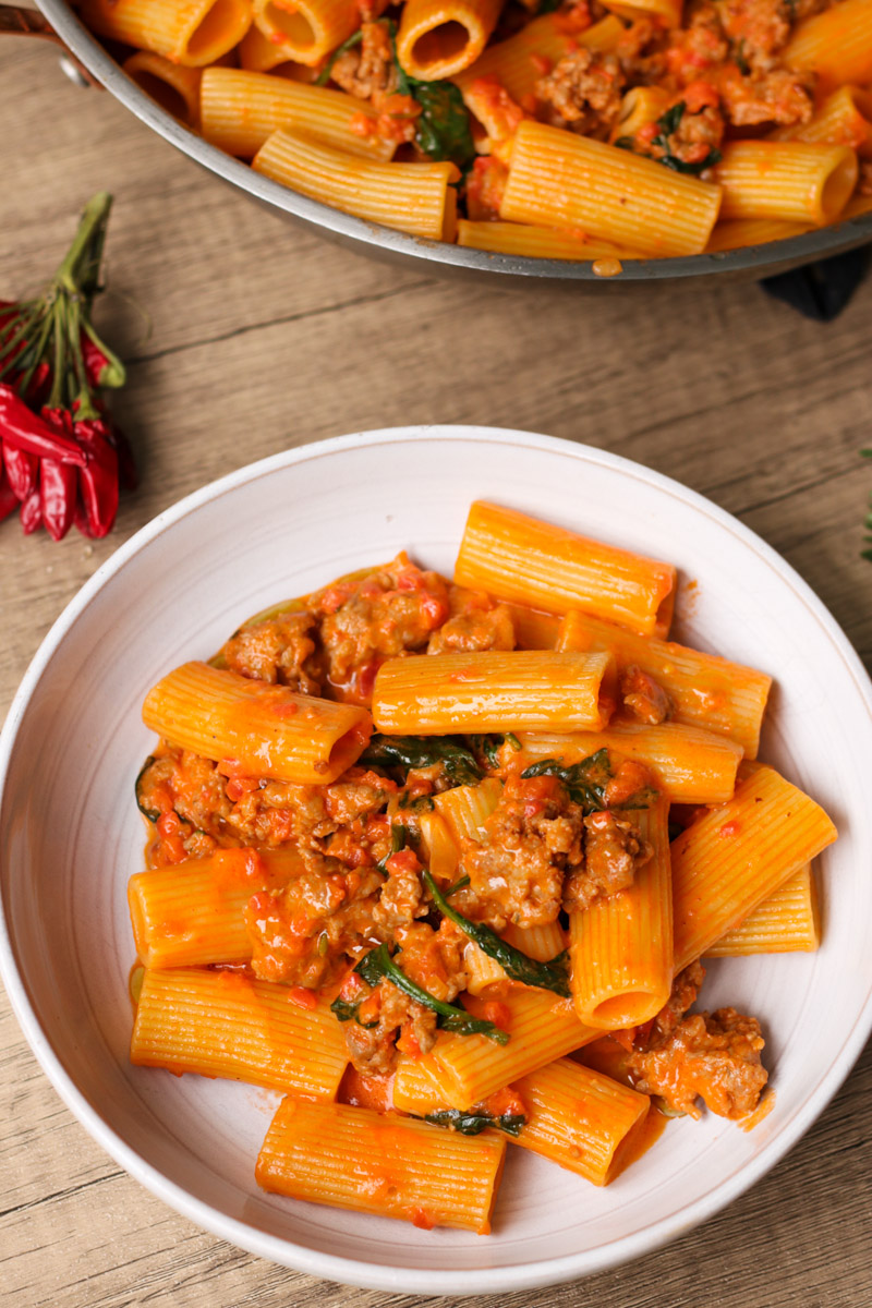 close up image of sausage rigatoni in a white bowl.