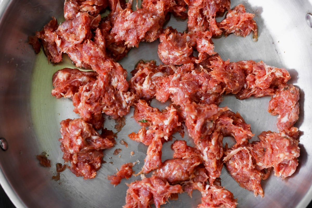 close up image of cooking sausage in a skillet.