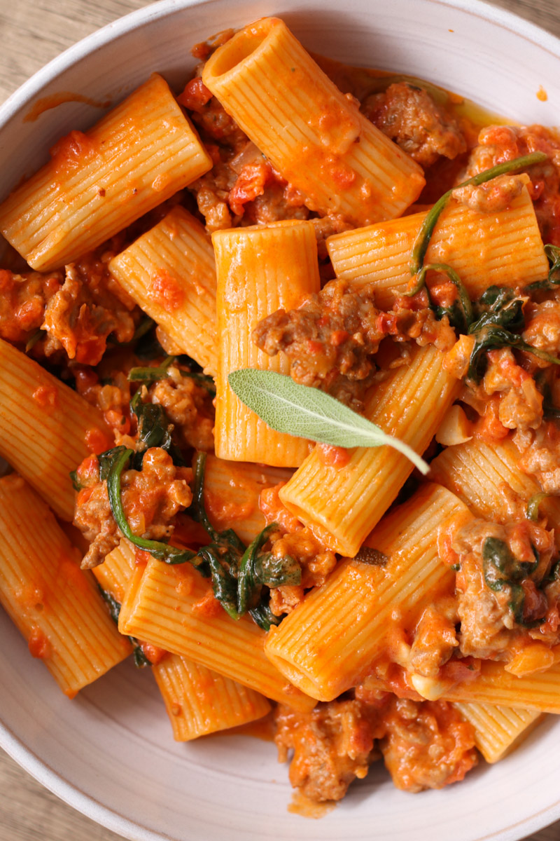 sausage rigatoni with creamy sauce in a white bowl.