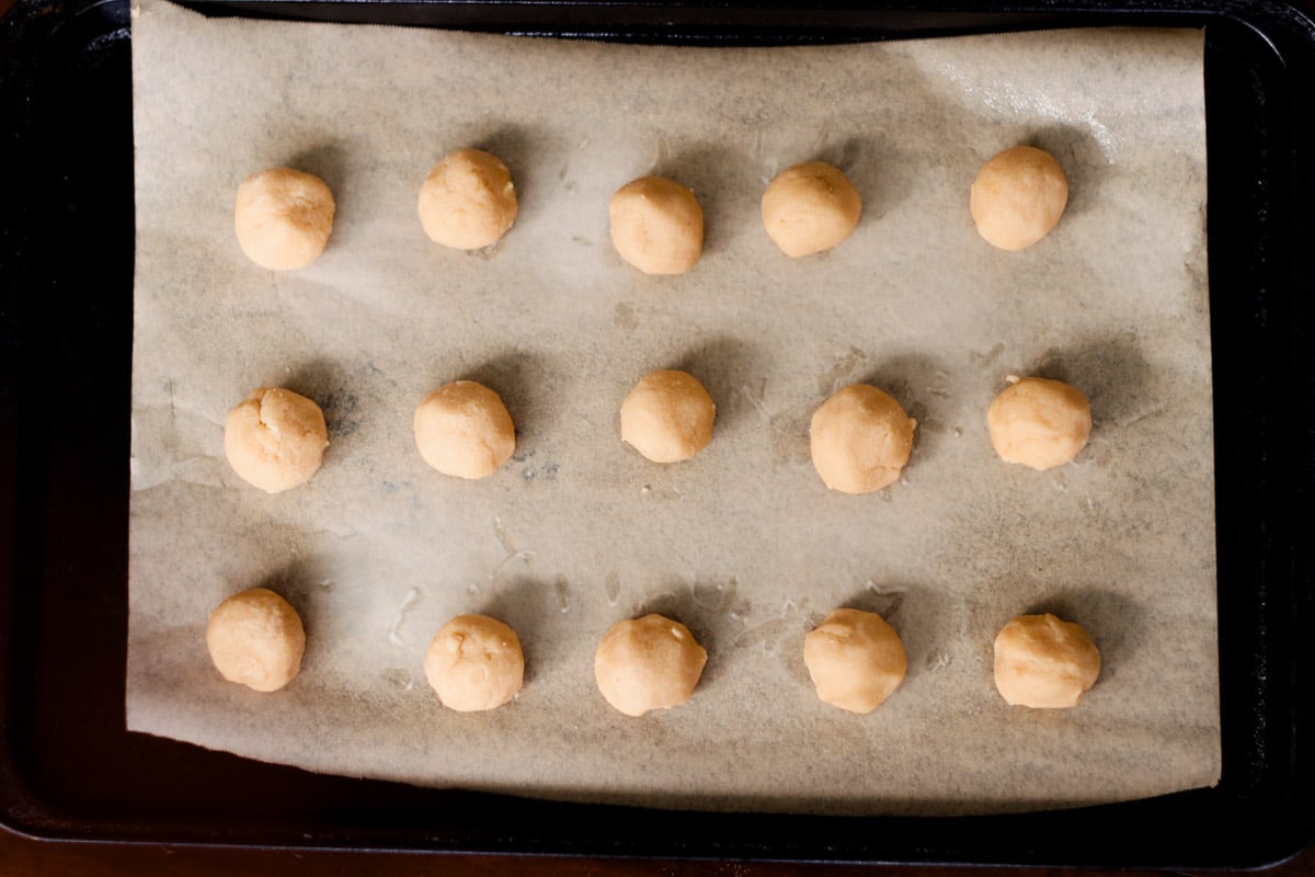 close up image of rolling cookie balls for almond thumbprint cookies.