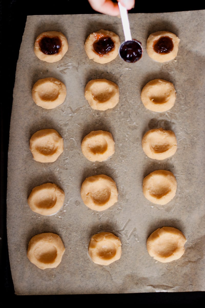 close up image of almond thumbprint cookies on a baking sheet.