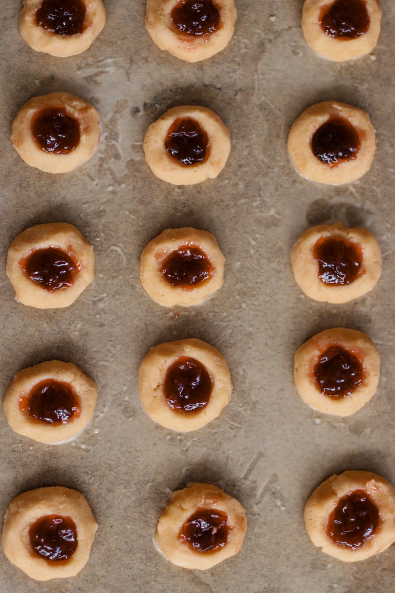 close up image of almond thumbprint cookies with jam.