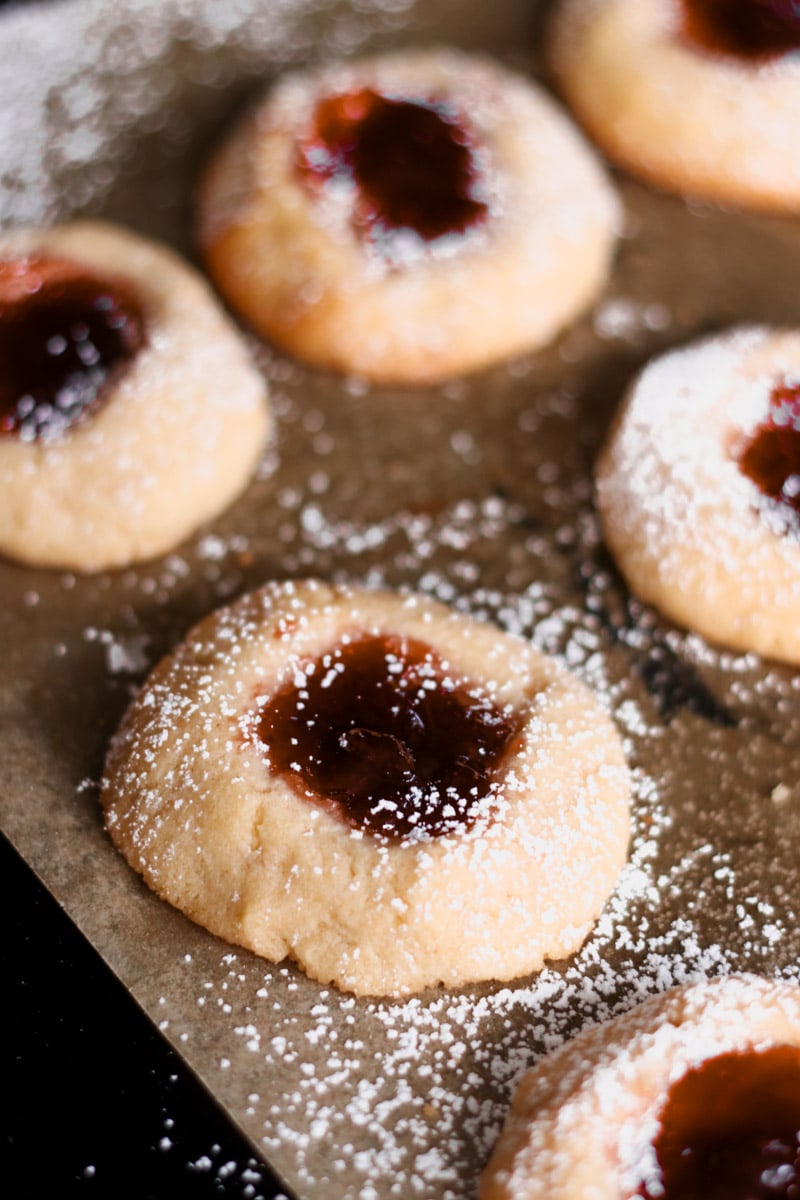 close up image of raspberry jam filled almond thumbprint cookies.