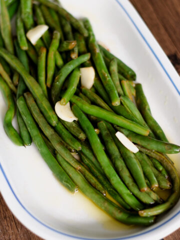 Sauteed greens beans on a white platter.