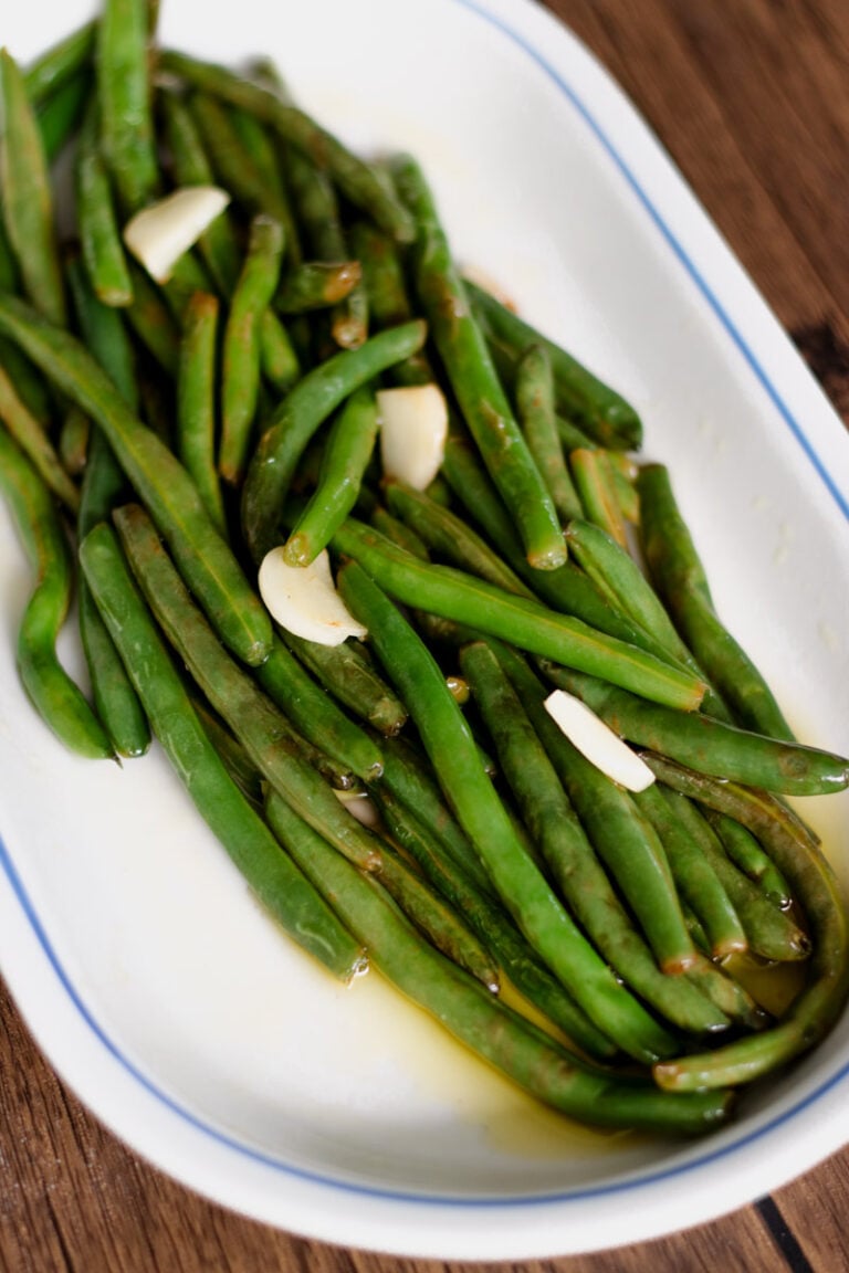 Sauteed greens beans on a white platter.
