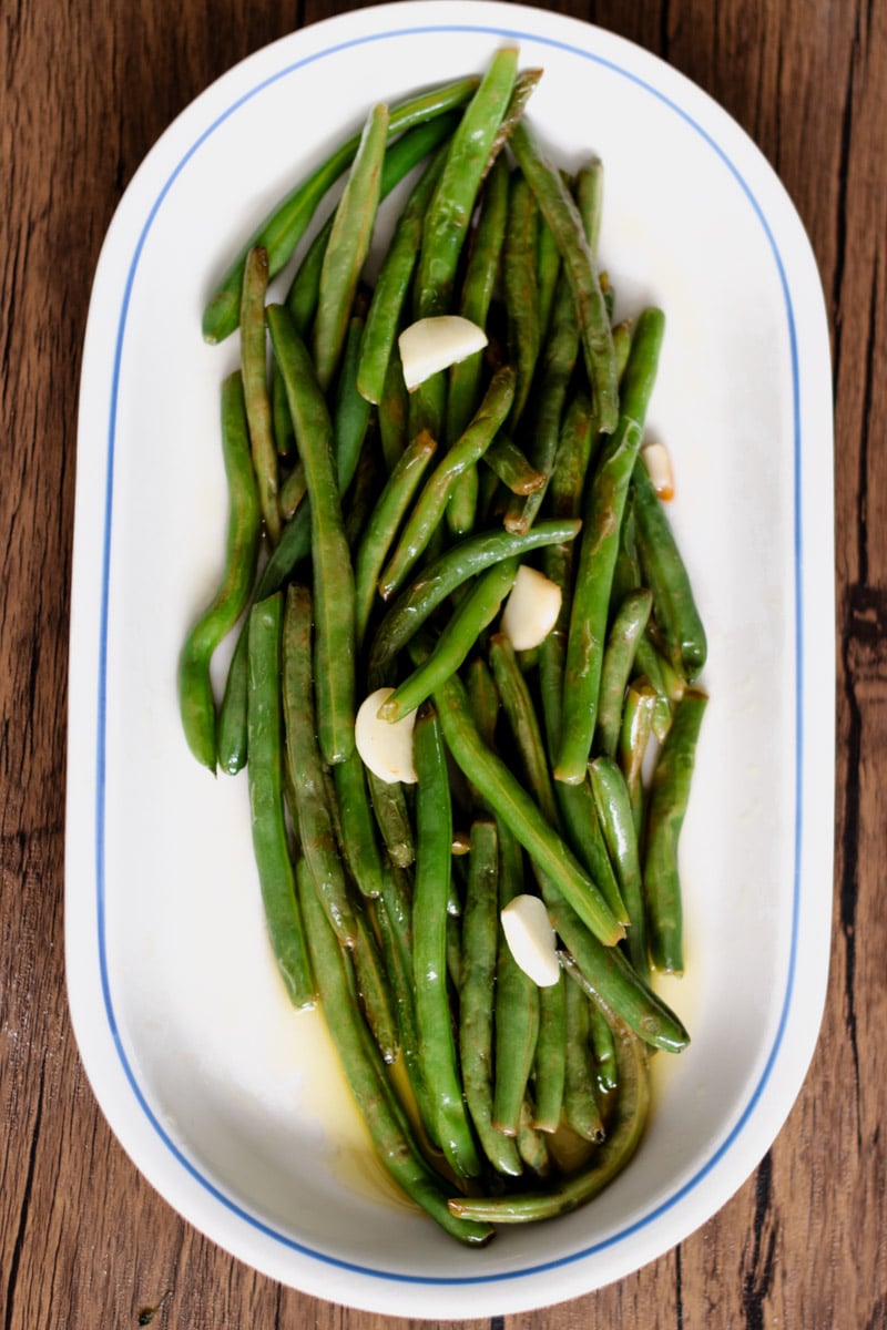 Sauteed greens beans on a white platter.
