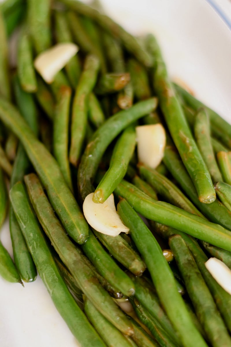close up image of Sauteed greens beans on a white platter.